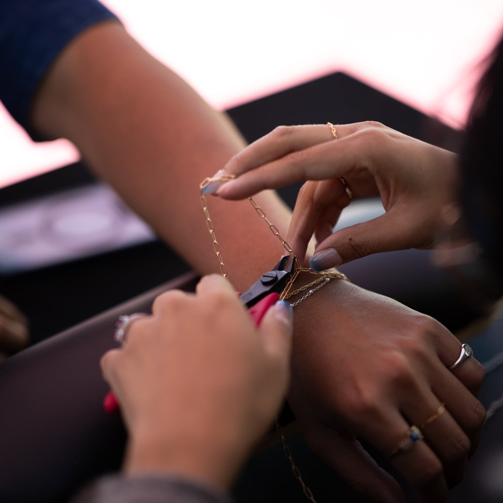 A close-up shot of the custom sizing process for a gold paperclip chain bracelet during a permanent jewelry activation with Hey Beautiful.