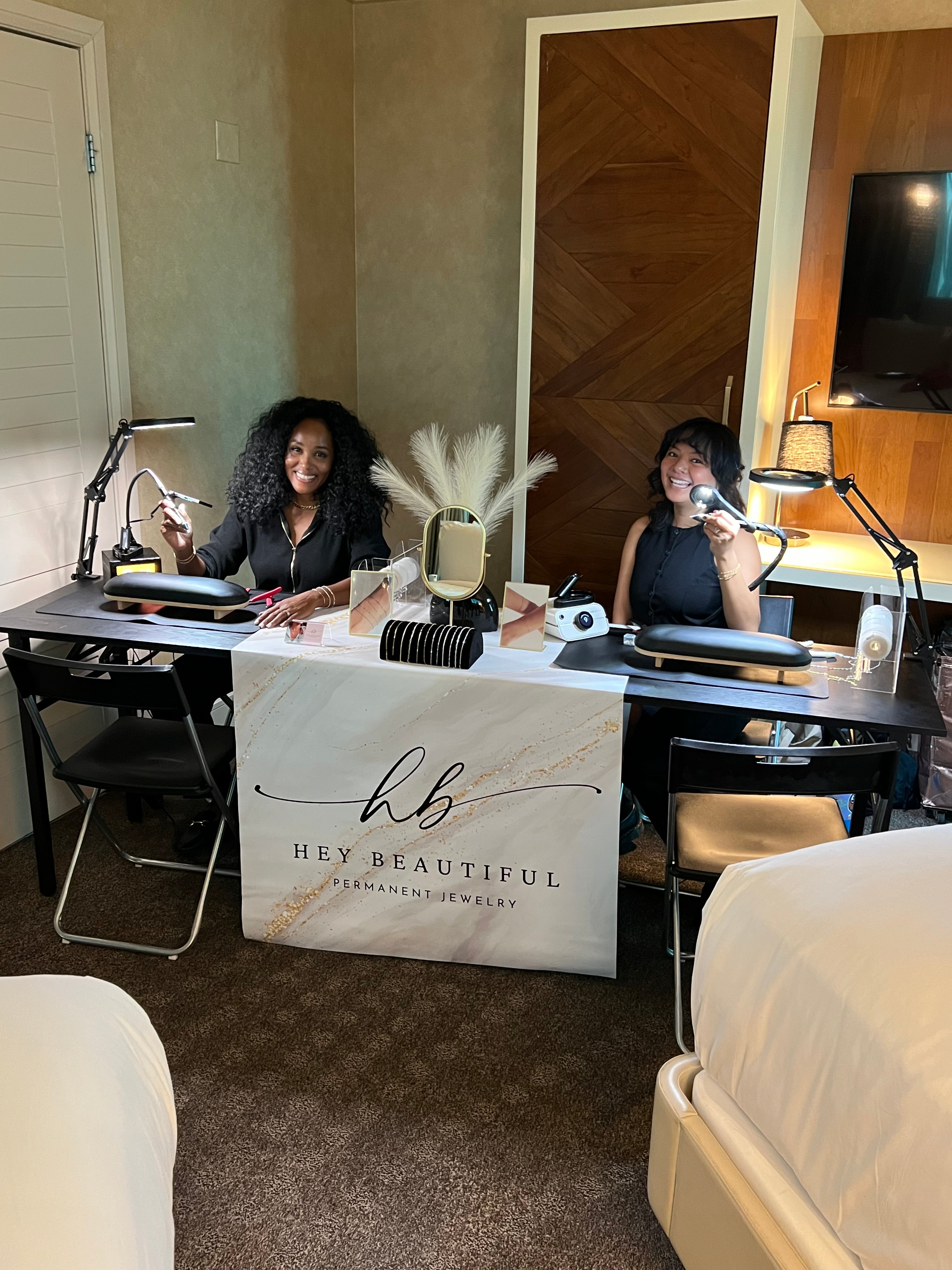 Hey Beautiful mobile permanent jewelry station setup with a custom branded banner for a private hotel suite event in Las Vegas.