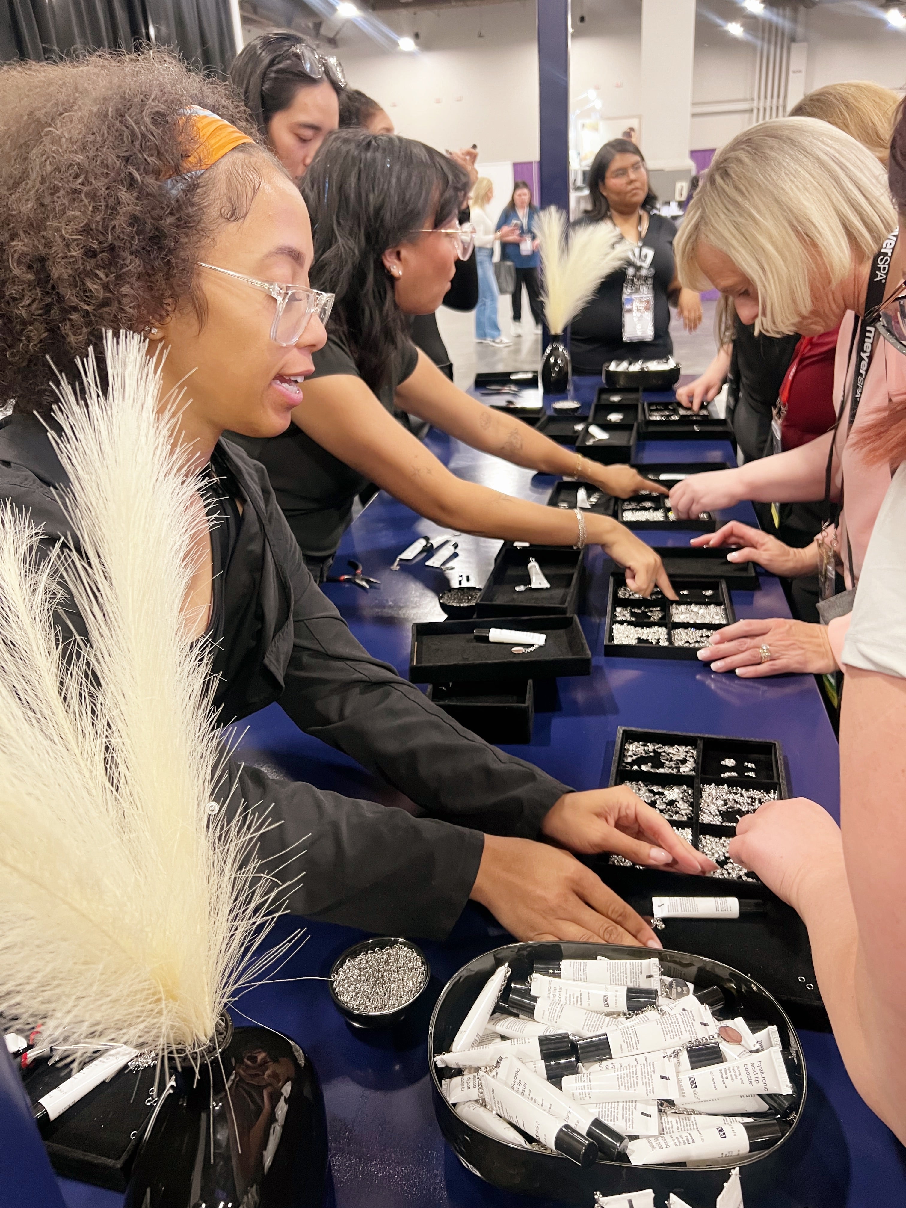 The Hey Beautiful team assisting a crowd of corporate event attendees at a high-volume  lip balm charm bar station.