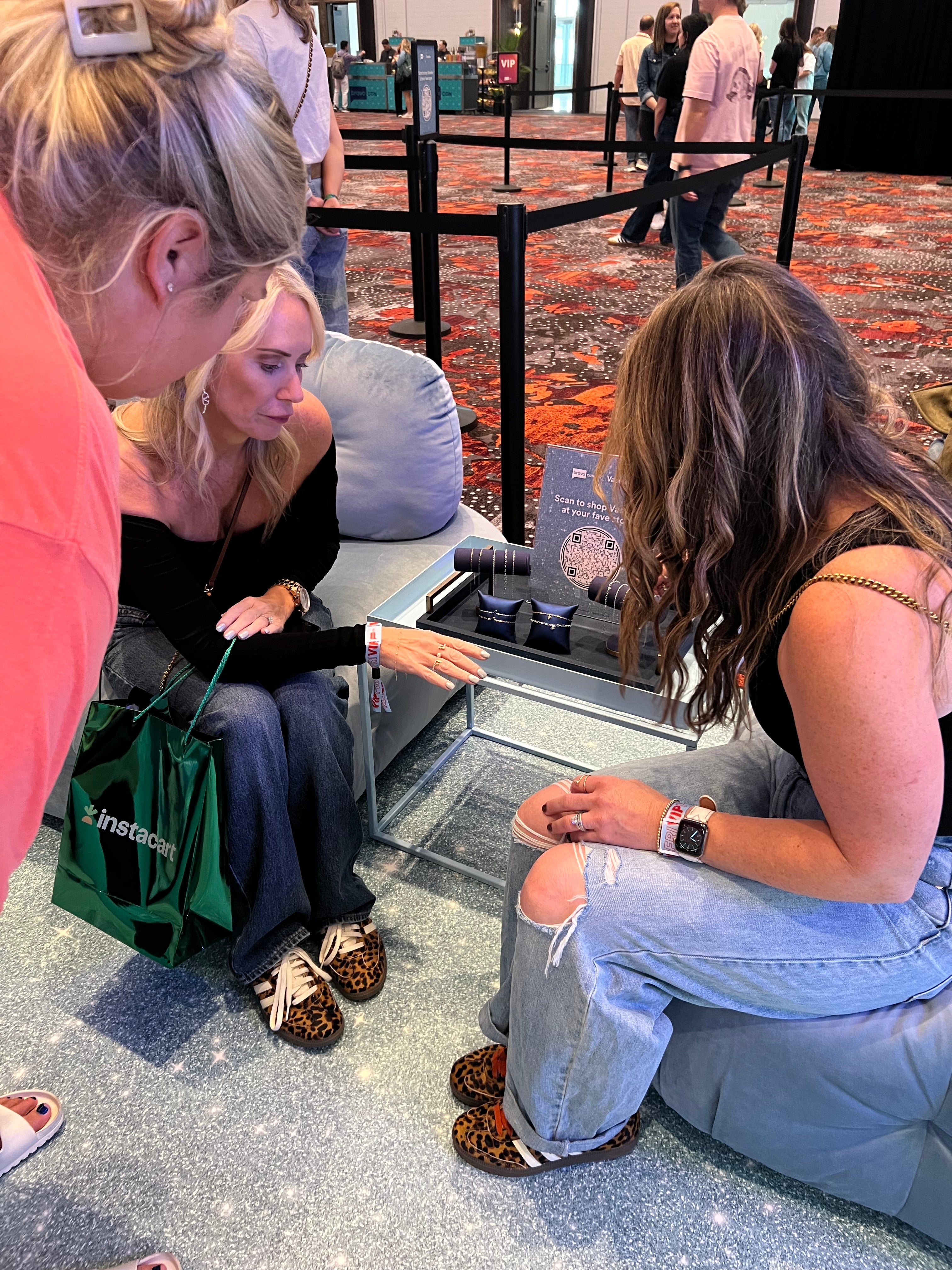 Two women sitting at the Vaseline booth looking down at chains for custom bracelets