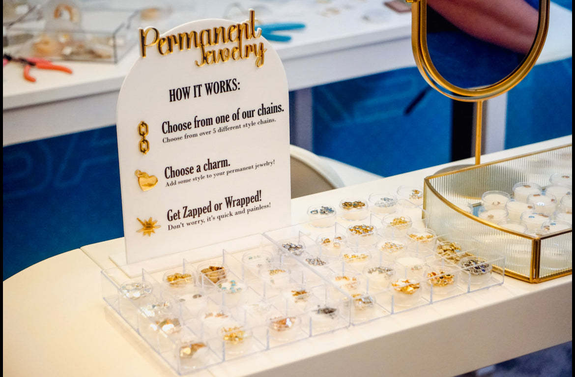 Display of jewelry with a sign explaining the process, including chains and charms, on a table.