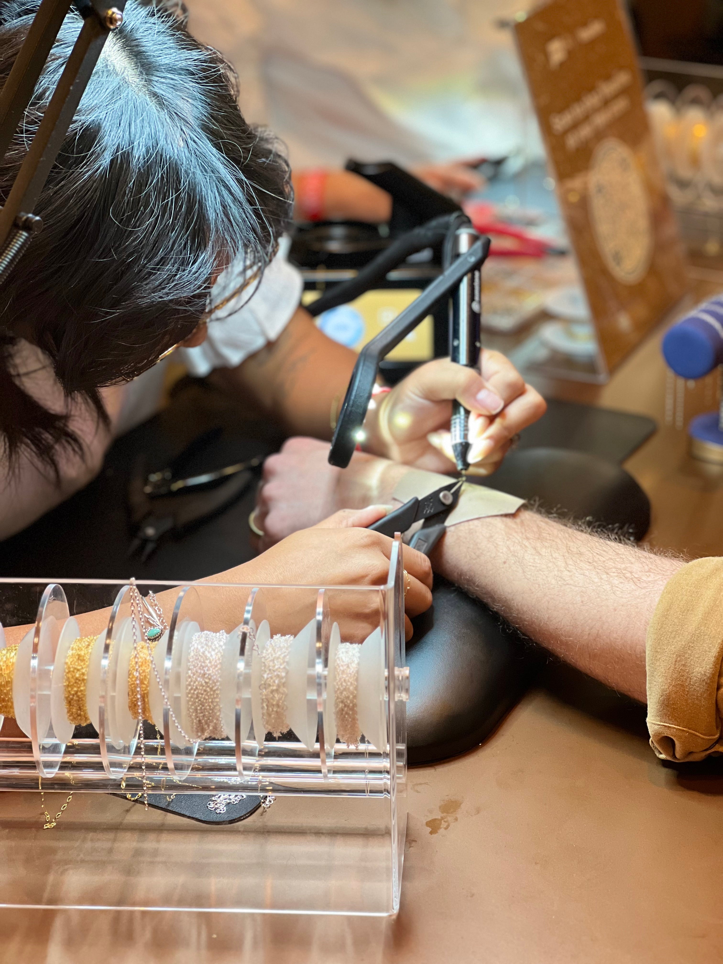 Guest getting a welded permanent jewelry bracelet at the Vaseline activation during BravoCon