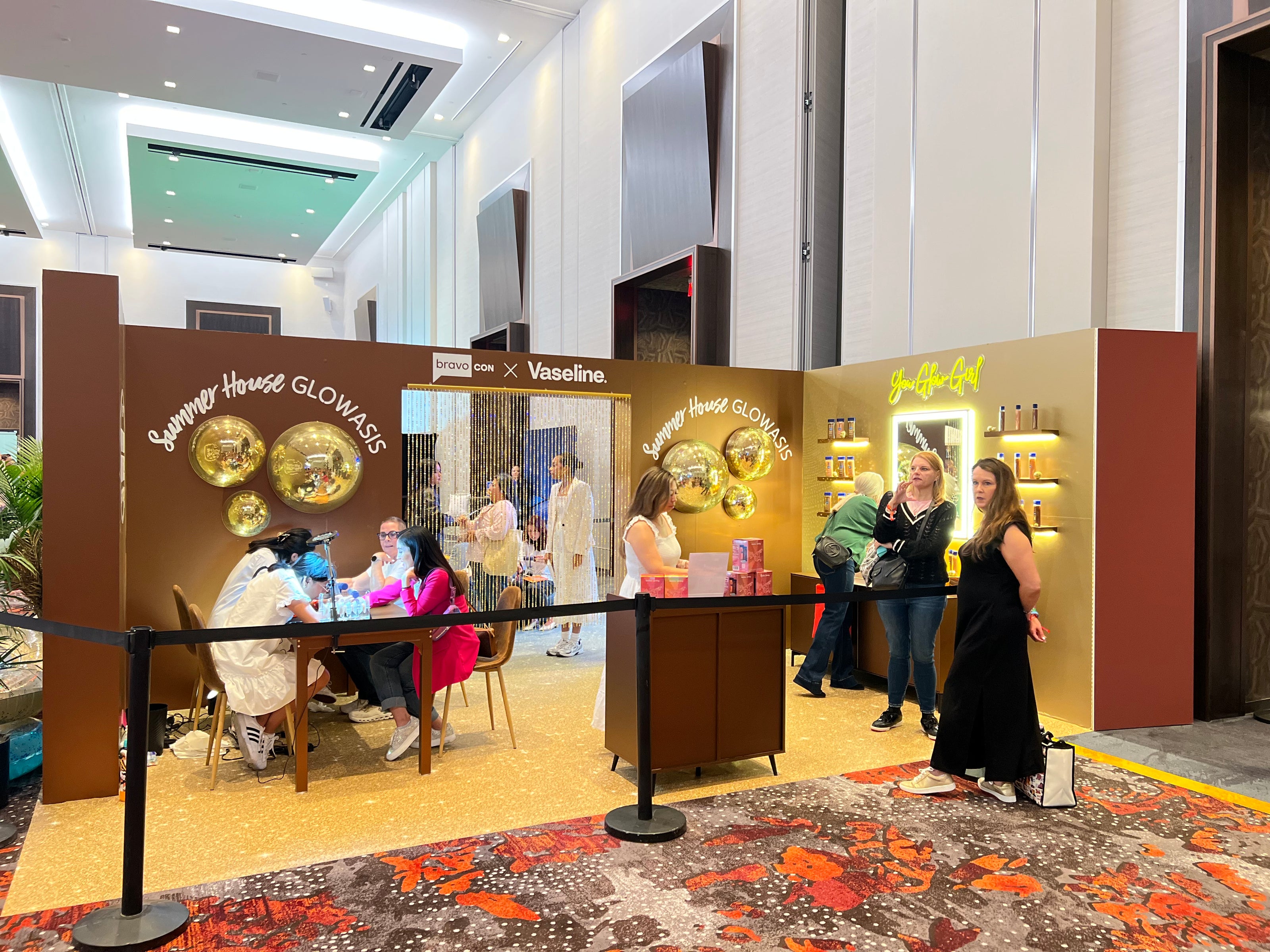 Event or exhibition setup with branded booths and people interacting inside a building.